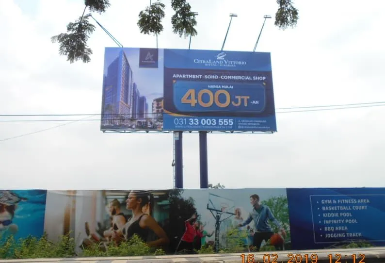 Billboard CitraLand Vittorio di atas pagar branding bergambar fasilitas olahraga