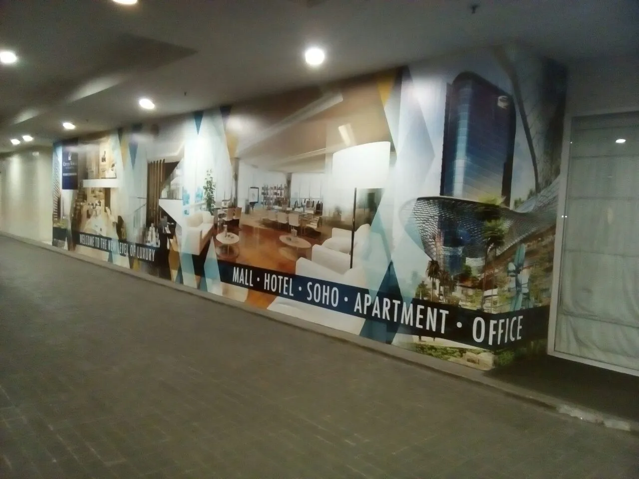Wall branding CitraLand sepanjang koridor dalam ruang menampilkan visual mall, hotel, SOHO, apartemen dan office