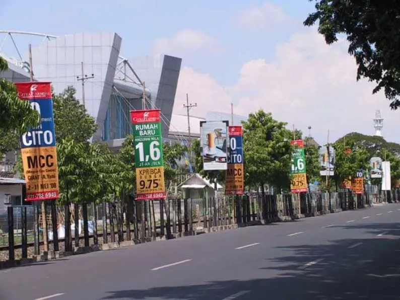 Deretan street banner promosi properti terpasang berurutan di sepanjang median jalan di Surabaya